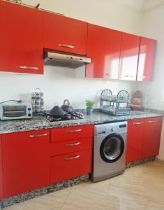 a kitchen with red cabinets and a washing machine at APPARTEMENT DE LUXE 3 Façades in Ben Slimane