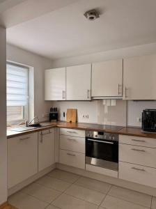 a kitchen with white cabinets and a stove top oven at Ferienwohnung BungertOase in Saarburg