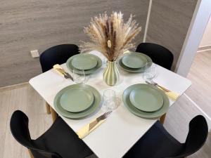 a white table with green plates and wine glasses at Pura Vida Apartment in Mostar
