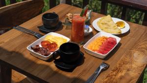a wooden table with breakfast foods and drinks on it at Nari Swari Sidemen in Karangasem +32 photos