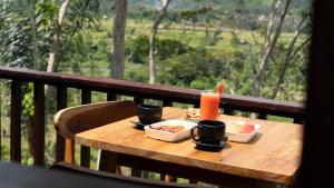 a wooden table with two plates of food and a candle at Nari Swari Sidemen in Karangasem