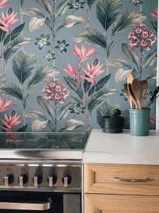a kitchen with a wallpaper with flowers on the wall at Le Marronnier in Montchauvet