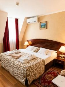 a bed in a hotel room with towels on it at Batthyány Kastélyszálló in Zalacsány