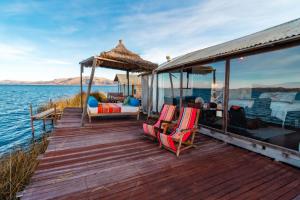 a wooden deck with chairs and a gazebo on the water at Uros Titicaca Kurmi lodge in Puno