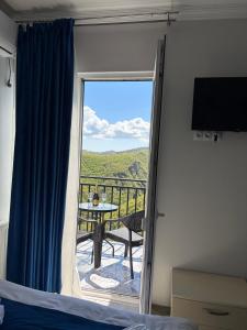 a bedroom with a bed and a balcony with a table at Panorama in Sighnaghi