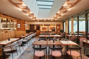 a restaurant with wooden tables and chairs and windows at voco Budapest D8 by IHG in Budapest
