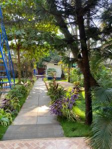 a walkway in a garden with trees and flowers at Anthony Stays Anjuna in Anjuna