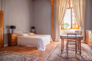 a bedroom with a bed and a desk and a table at Château du Hardas in Segré