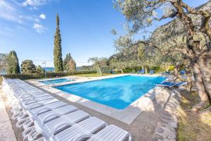 a swimming pool with white lounge chairs next to a tree at TINA HOME LAKE VIEW in Garda