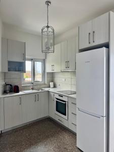 a kitchen with white cabinets and a white refrigerator at GA apartments in Kato Pyrgos +8 photos
