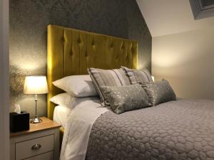a bedroom with a bed with a yellow headboard and pillows at Christmas Hill Farm in Gaydon