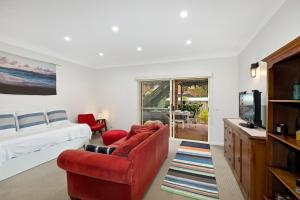 a bedroom with a bed and a tv and a red chair at Family stay minute walk from Hargraves beach in Norah