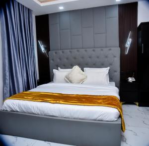 a bedroom with a large bed with a large headboard at Orchid - Bliss Hotels in Lagos