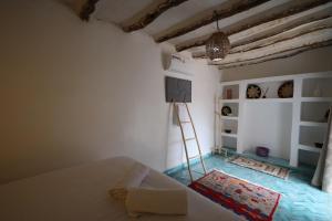 a room with a bed and a ladder and a tv at Bohemian lodge guest house in Aït Namous
