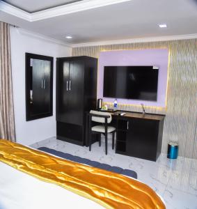 a hotel room with a desk and a flat screen tv at Orchid - Bliss Hotels in Lagos