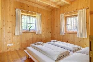 two beds in a wooden room with two windows at Ferienhaus Schwarzenbach in San Genesio Atesino