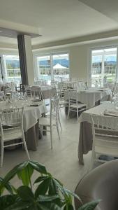 a restaurant with white tables and chairs and windows at Tenuta il Bandito in Montesano Scalo