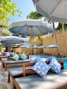 a group of tables with umbrellas next to a pool at Wild Orchid Krabi in Ao Nam Mao