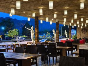 a restaurant with tables and statues in the background at Wild Orchid Krabi in Ao Nam Mao