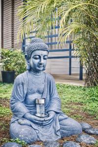 a statue of a buddha sitting on some rocks at Emeraude tropicale in Goyave