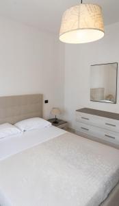 a white bedroom with a bed and a mirror at A Due Passi dal Mare in Chioggia