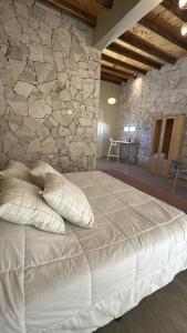 a bedroom with a large bed with a stone wall at Rio los Patos in Barreal