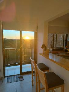 a kitchen with two chairs and a window with the sunset at Departamentos M&A 1 in Puerto Rico