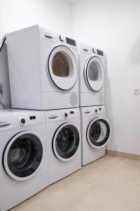 three washers and dryers are stacked in a laundry room at Casa do Santo Estevão in Macedo de Cavaleiros