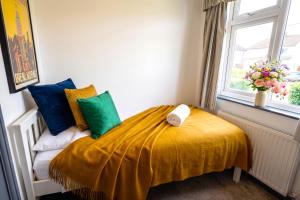 a bedroom with a bed with a yellow blanket and a window at Green Haven Villa - 4BR Spacious House with Hot tub, Ample Parking, Air Condition, WIFI, Netflix, Patio & Garden in Oxford
