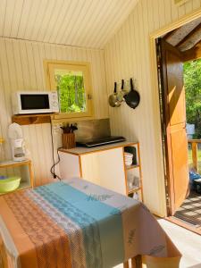 a small kitchen with a bed and a microwave at Camping Le Vert-Bois - Corrèze in Saint-Martin-la-Méanne