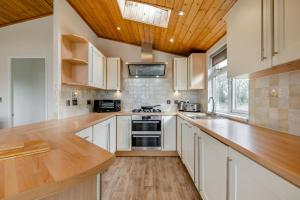 a kitchen with white cabinets and a wooden ceiling at Field View 2 bed - Hazel in Eye