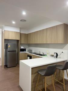 a kitchen with a white counter top and wooden cabinets at Second Home - A modern 4 Bedrooms House in Blacktown