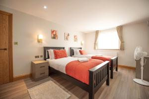a bedroom with a bed with orange sheets and a window at Hazel Lodge in Reading