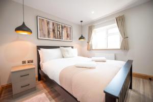 a bedroom with a bed with white sheets and a window at Hazel Lodge in Reading