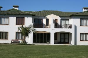 a large white building with a palm tree in front of it at Keurbooms River Lodge 1115 in Plettenberg Bay