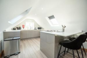 a white kitchen with a counter and stools at Hazel Lodge in Reading +22 photos