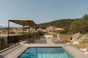 a swimming pool with a deck and chairs and a house at Villa Nebbiu Vista in Oletta