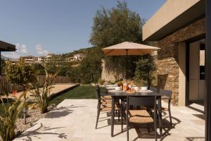 a patio with a table with an umbrella at Villa Nebbiu Vista in Oletta