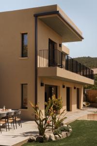 a house with a balcony and a table and chairs at Villa Nebbiu Vista in Oletta