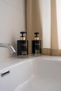 two bottles of soap sitting on top of a bathroom sink at Dante Suites in Pergola +146 photos