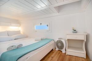 a white bedroom with a bed and a window at Anna's Apartment Marmara Paros in Kampos Paros