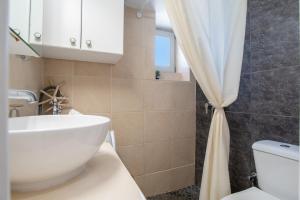 a bathroom with a white sink and a shower curtain at Anna's Apartment Marmara Paros in Kampos Paros +15 photos