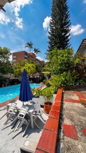 a pool with chairs and an umbrella and a tree at Hotel Premium Real in Medellín