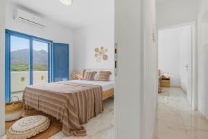 a white bedroom with a bed and a large window at Cassiopeia in Akrotiri