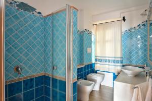 a blue tiled bathroom with a toilet and a sink at Villa Janas in Baunei