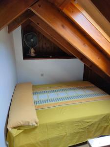 a yellow bed in a room with wooden ceilings at Barruera duplex 2 bedrooms heating in Barruera