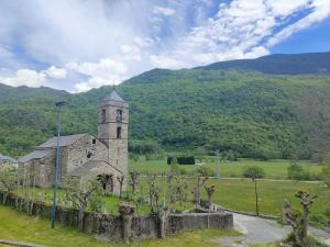 an old church in a field with mountains in the background at Barruera duplex 2 bedrooms heating in Barruera