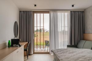 a bedroom with a bed and a desk and a window at MARSHALL Golf & Wellness Hotel in Sokolov