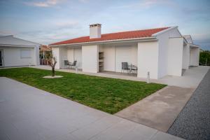 a white house with a green lawn in front of it at Casa do Pôr do Sol in Macedo de Cavaleiros
