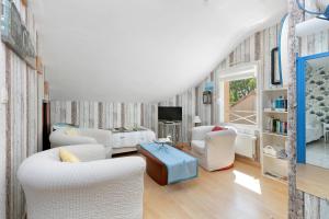 a living room with white chairs and a tv at Chez Anne-Marie et Constant in Pornichet